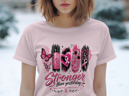 Pink t-shirt with a graphic of a butterfly, water bottle, heart, shoes, and tree with pink ribbons.