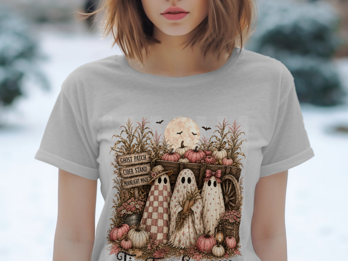 Three ghosts stand near a wagon with pumpkins and corn stalks under a full moon.