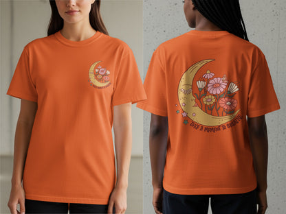 Orange t-shirt with celestial moon and flowers graphic that says "take a moment to breathe."