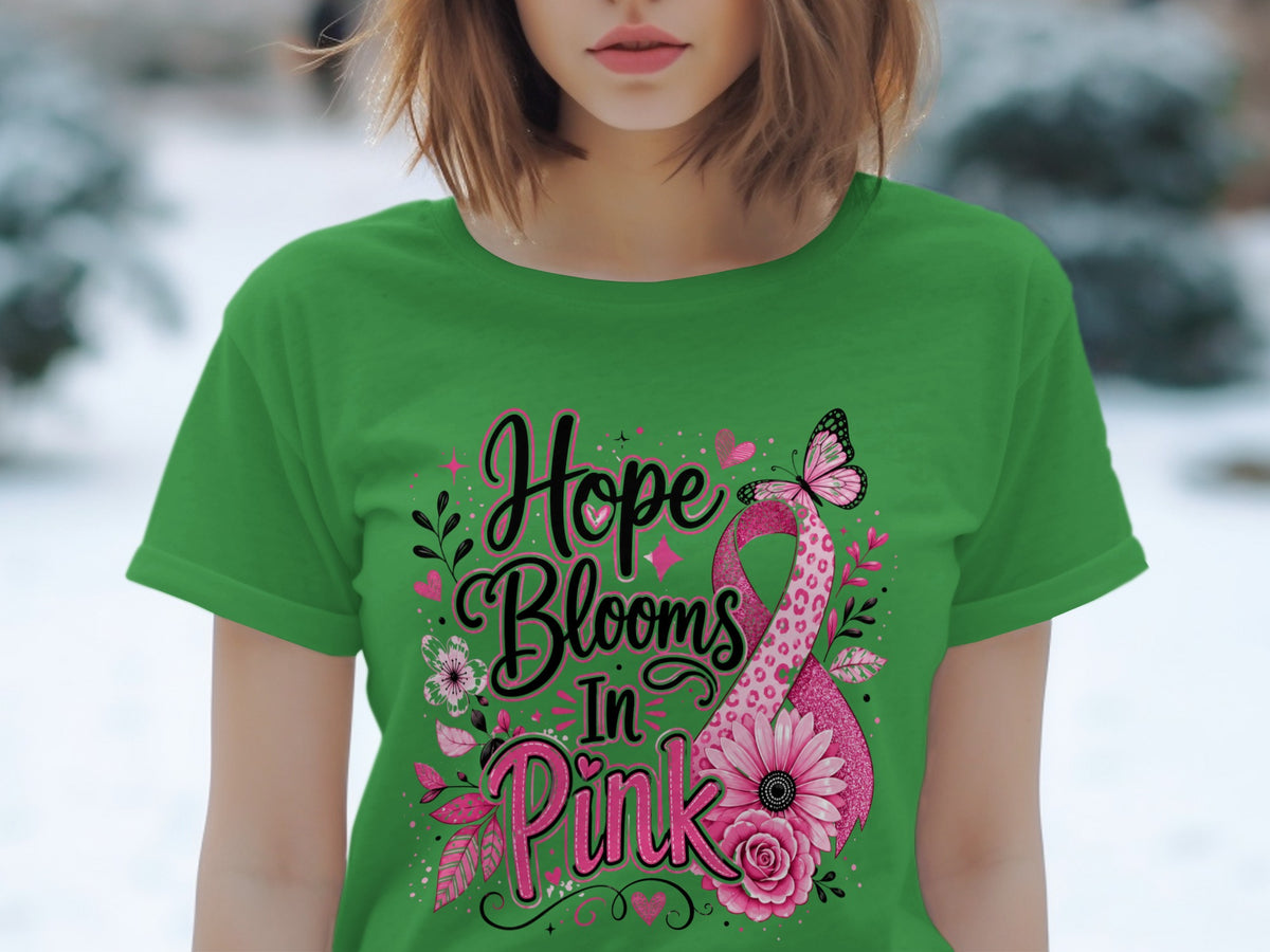 Green t-shirt with "Hope Blooms In Pink" text and pink ribbon design.