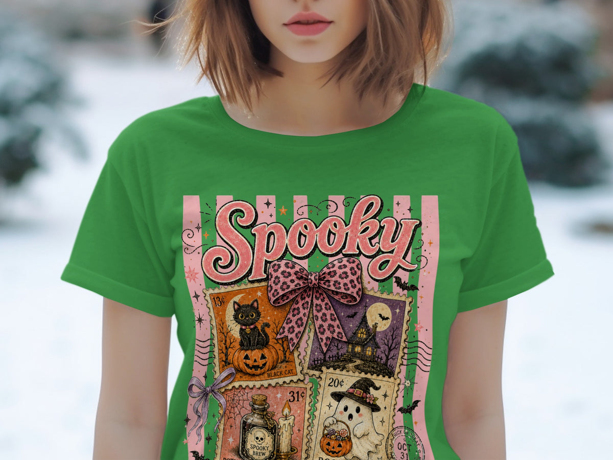 Green t-shirt with Halloween postage stamp-themed graphic featuring a black cat, haunted house, ghost, and potion.