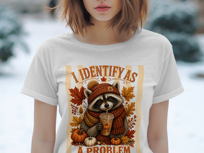 Raccoon in autumn attire drinking from a cup with text "I IDENTIFY AS A PROBLEM".